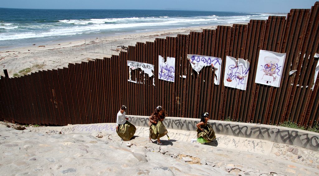 Girls playing on a beach in TIjuana near the US-Mexico border fence.
